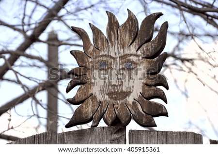 Wooden smiling sun. Retro element of decor on a wooden fence 