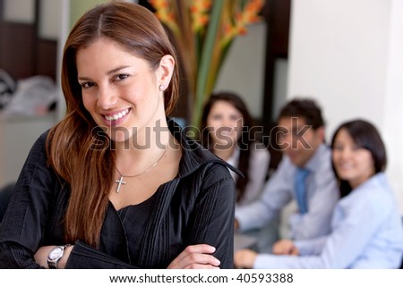 Business woman smiling in an office with her team behind her
