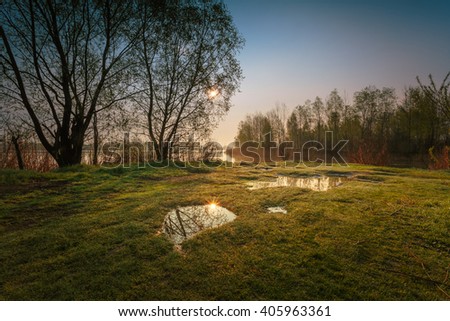Morning april landscape with puddles on foreground and lake coast on background.
