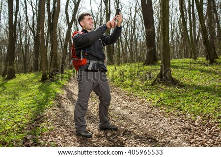 Man hiker taking photo with smart phone in forest