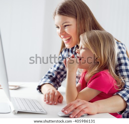 Portrait of laughing mom and little girl watching cartoon movie at computer. Concept of family leisure activity and lifestyle.  