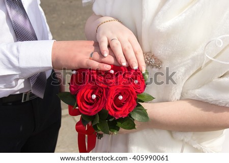 Hands newlyweds on a bouquet