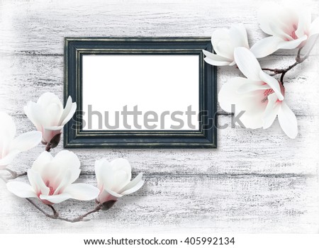 White magnolia flowers and photo frame on background of shabby wooden planks in rustic style