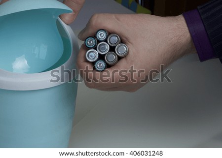 Disposal of batteries in the container. Man holds in one hand and used batteries. With the other hand opens the container for disposal.