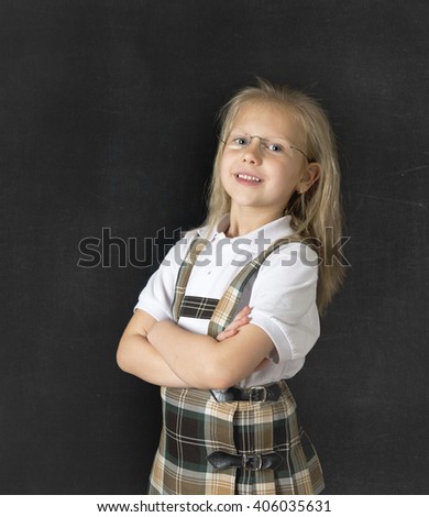 young sweet junior schoolgirl with blonde hair standing and smiling happy  isolated in blackboard background wearing school uniform in children education success and fun