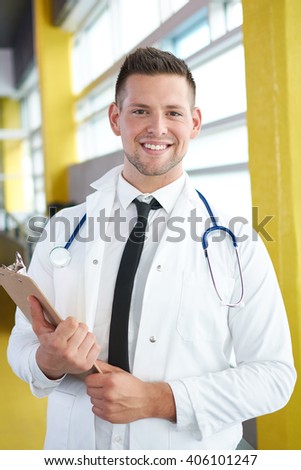 Portrait of a male doctor holding his patient chart in bright modern hospital