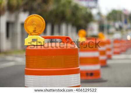 long line of orange traffic barrier barrels to detour traffic around construction zone shallow depth of field