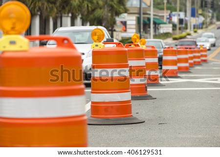 long line of orange traffic barrier barrels to detour traffic around construction zone shallow depth of field