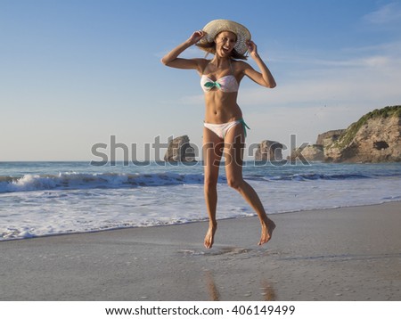 Happy blonde girl on swimwear jumping on the beach at seaside