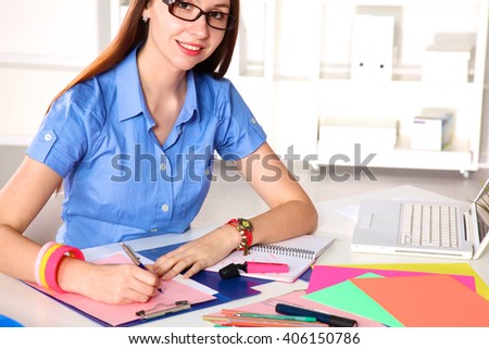 Young graphic designer working on laptop using tablet at home