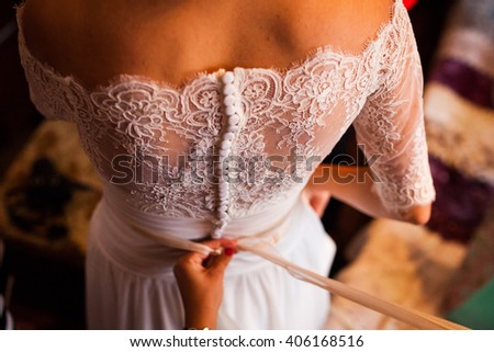 Bridesmaid tying bow on wedding dress Royalty-Free Stock Photo #406168516