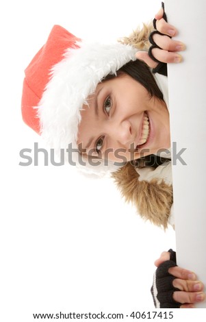 Portrait of a beautiful woman in santa hat holding a blank billboard looking out from behind it.