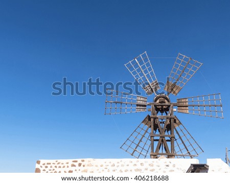 A six wing rectangular female windmill on the Canary Islands, located in the center of the island pictured against deep blue sky.