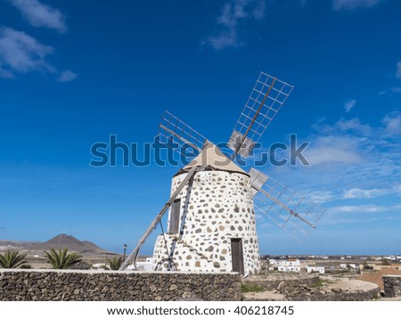 A four wing round male windmill on the Canary Islands, located in the center of the island pictured against deep blue sky.