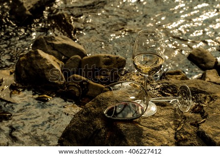 Wine glass with white wine standing on stone at seashore in sunset. Vintage look