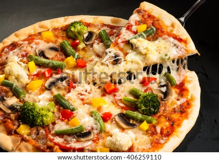 vegetarian pizza on a dark background with mushrooms, cheese and sweet pepper, cutting Royalty-Free Stock Photo #406259110