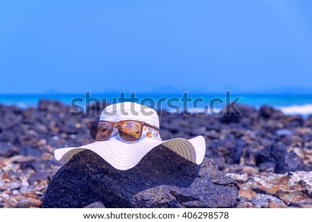 hat And sunglasses lying  on tropical sand beach Sunglasses on the beach. Beautiful sea view wallpaper, background Enjoyed a relaxing summer vacation concept.