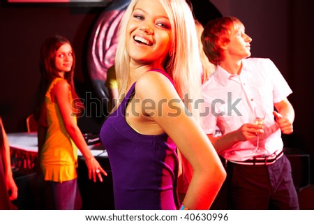 Image of energetic girl looking at camera while dancing on background of her friends
