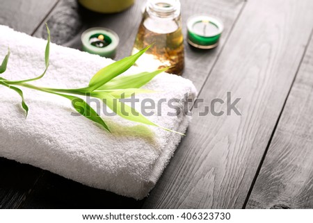 SPA still life with towel, candles and bamboo leaves on a black wooden surface Royalty-Free Stock Photo #406323730