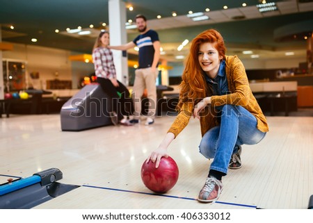 Beautiful woman bowling with friends getting ready to throw ball