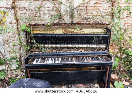 old piano with concrete wall and leaf
