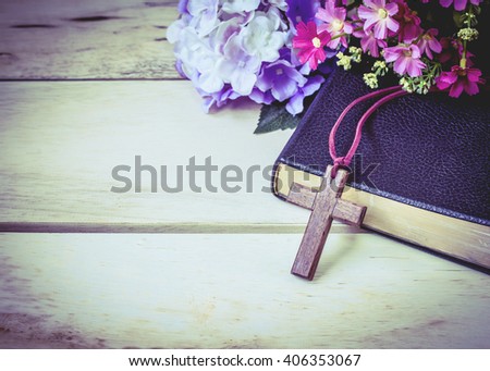 image of the wooden cross and black bible with flowers on wooden background
