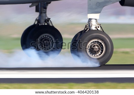 Airplane landing gear touching the runway with white smoke. Royalty-Free Stock Photo #406420138