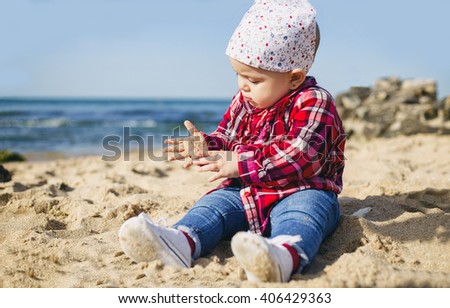 Baby girl playing in the sand on the beach. Ocean as background