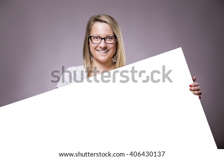 Portrait of a cheerful young caucasian woman holding a white blank banner.
