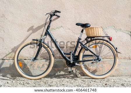 Black retro vintage bicycle. Retro bicycle with basket in front of the old wall. 