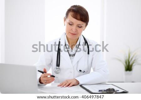 Woman doctor filling up medical history at the desk