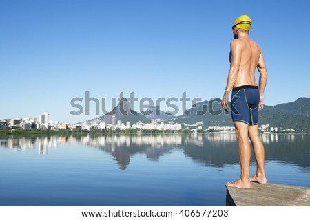 Athlete swimmer with gold swimming cap standing in front of the Rio de Janeiro skyline at Lagoa Rodrigo de Freitas lagoon