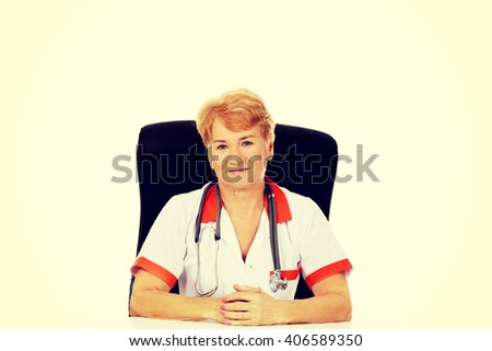 Smile elderly female doctor or nurse sitting behind the desk