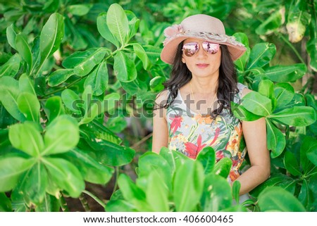 Portrait of a girl who is standing among the green leaves of the tree