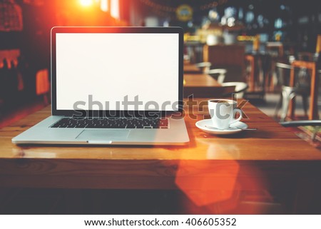 Open net-book and cup of cappuccino lying on table in cafe bar interior, laptop computer with blank copy space for your text message or promotional content, freelance remote job during coffee break 