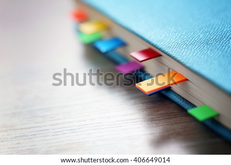 Blue dairy with multicoloured stickers on wooden background, closeup