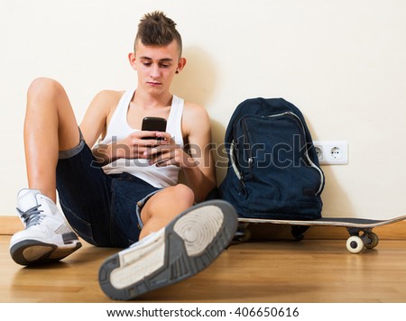 Young teenager burying in mobile phone and social networking indoors Royalty-Free Stock Photo #406650616