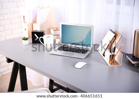 Workplace with laptop, table and books beside the window