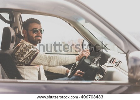 Young man drives a car in mountains. Travel and adventure concept. Toned picture