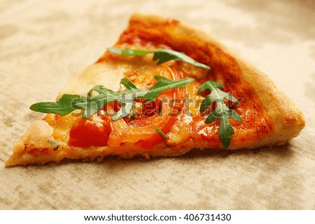 Margherita pizza slice with arugula on cardboard background