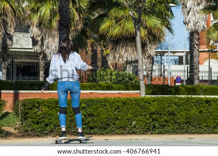 Beautiful young woman practicing with the skateboard on the street on a sunny day