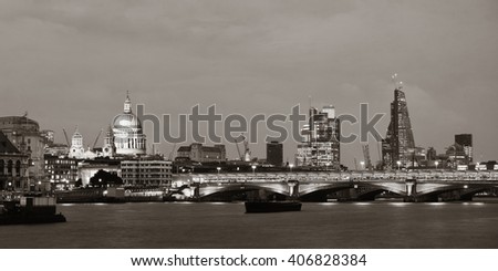 London skyline at night with bridge and St Pauls Cathedral over Thames River.