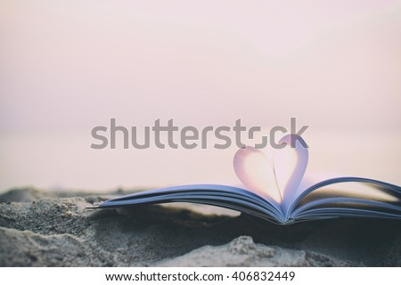 Close up heart shape from paper book on sand in the beach with vintage filter blur background Royalty-Free Stock Photo #406832449