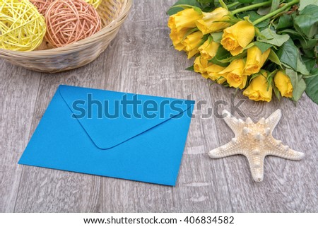 Envelope, white starfish and roses on a wooden background