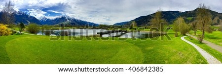 Beautiful golf resort with wooden bridge across the lake in Zell am See in Alps with big mountains behind