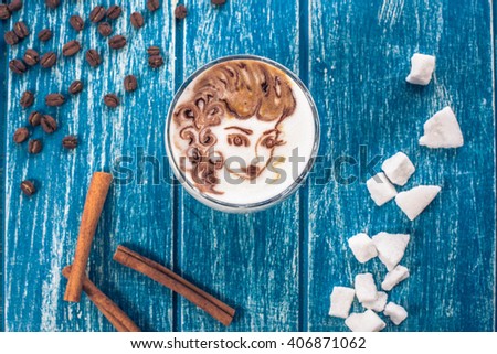 Cup of coffee with picture of woman face on the table with a coffee beans and sugar