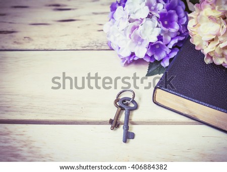 old metal keys and black bible with flowers on wooden background, concept