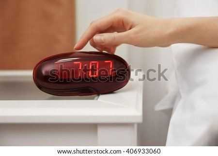 Female hand trying to stop digital clock ringing