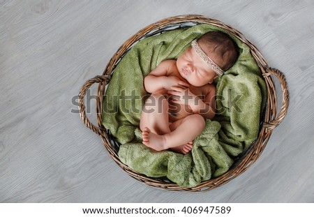 Close-up beautiful sleeping baby girl. Newborn baby girl, asleep on a blanket. A portrait of a beautiful, seven day old, newborn baby girl wearing a large, fabric rose headband. Closeup photo