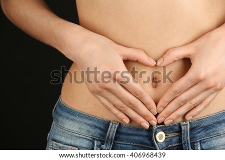 Hands forming heart on female belly button. Healthy stomach health concept, or early pregnancy concept Royalty-Free Stock Photo #406968439